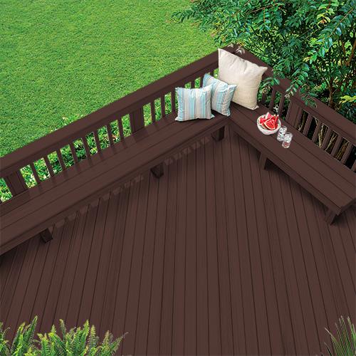 Outdoor dark brown wooden deck with bench and colored pillows around grass and trees