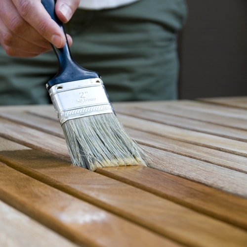 Paint brush being used to stain a wood surface